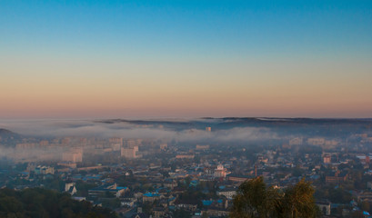 Dawn over the city in the fog