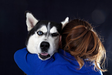 Woman hugs dog breed Siberian Husky on black background