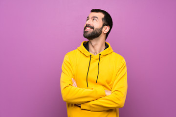 Handsome man with yellow sweatshirt looking up while smiling