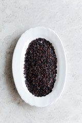 Fototapeta na wymiar Black wild rice in a white plate close-up on a white background, selective focus