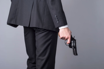 portrait of a man in a business suit with a gun. On a gray background.