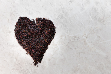 Black wild rice heart-shaped close-up background texture top view, selective focus