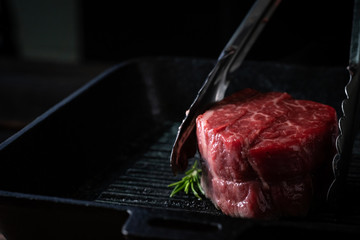 Chef roasts filet Mignon beef steak in a pan with tongs
