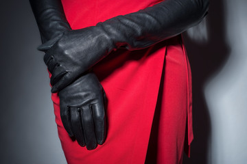 Close-up of a girl in a red designer skirt, with black leather gloves. Fashionable look....