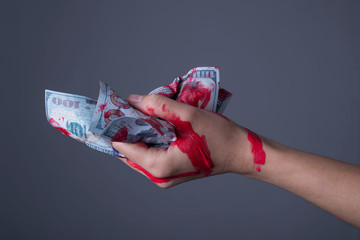 Closeup, girl clenching a fist. holds bloody dollar crumpled dollar bills, on gray background