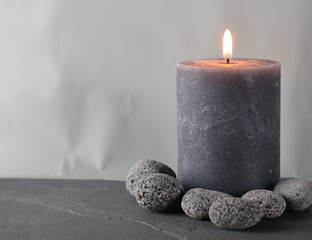 a gray wax candle surrounded by pebbles