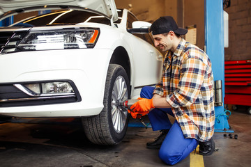 Obraz na płótnie Canvas repairman changing wheel on car using pneumatic wrench in the garage