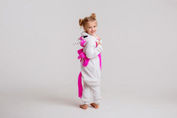 little blonde girl in kigurumi on white background, space for text.modern fashion -children girl posing on a white background in kigurumi pajamas, bunny costume