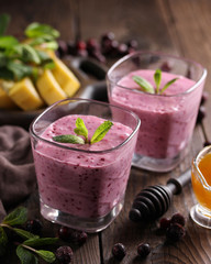 The concept of healthy cuisine. Smoothies with kefir, berries, banana and honey on a dark wooden background. Background image, copy space