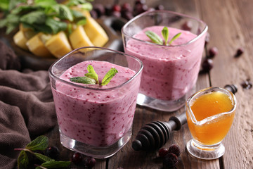 The concept of healthy cuisine. Smoothies with kefir, berries, banana and honey on a dark wooden background. Background image, copy space