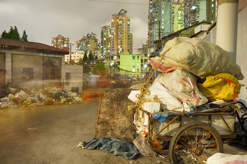 Outdated waste management system in popular residential district in Shanghai. Trash deposed directly on street, recycled stuff charged at old tricycle.