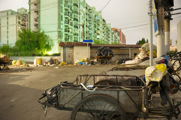 Outdated waste management system in popular residential district in Shanghai. Trash deposed directly on street, recycled stuff charged at old tricycle.