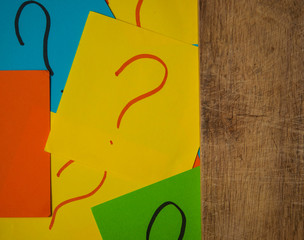 Stack of colorful cards with a question mark on the old wooden background