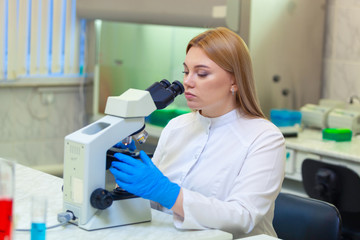 Laboratory assistant working with a microscope in a scientific laboratory.