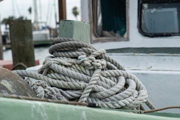 Fototapeta premium Rope piled up on deck of an old fishing boat in marina, in close up with limited focus and shallow depth of field.