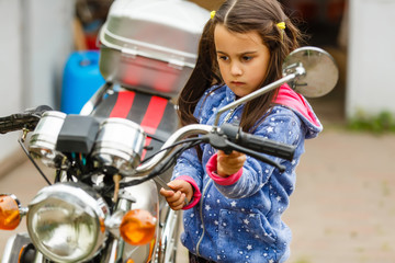 Obraz premium little girl repairing a motorcycle, Student girl in motorbike mechanics