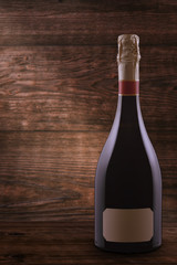 Single champagne bottle with blank label on a wooden table on a background of vintage textured wooden planks with copy space