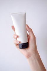 Young female hand holds minimalistic mockup cosmetic packaging. Mock-up for branding and label.