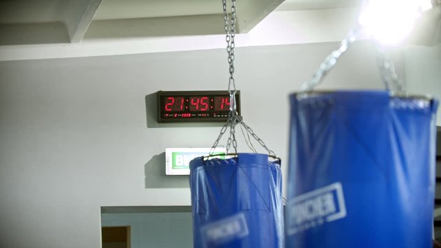 A timer on the wall in the gym - punching bags hanging on the foreground