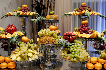 Obraz na płótnie Canvas Fresh organic fruits background. Healthy eating concept. Fresh, exotic, organic fruits, light snacks in a plate on a buffet table. Luxury wedding catering. Delicious fruit at wedding reception.