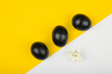 three black eggs on a yellow-white background. flat lay. Black Easter. three black eggs