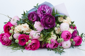 on a light background a bouquet of ranunculuses and roses