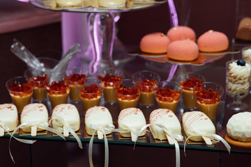 Sweet buffet for birthday party or wedding. Delicious wedding reception candy bar dessert table, cake. Delicious cupcakes with cream cheese frosting, candies and meringues.