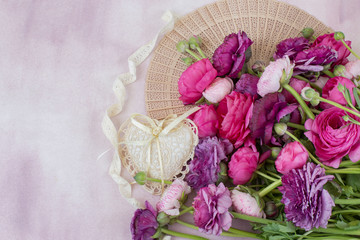 on a pink background a bouquet of ranunculus fan, heart of lace, lace ribbon