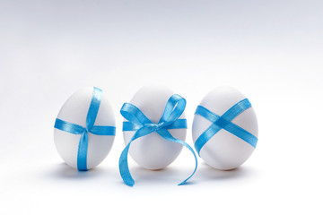 White eggs with blue ribbon on white background. Happy easter. New life concept. Holiday card.