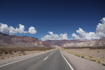 długa płaska droga asfaltowa ciągnąca sie po horyzont z górami i niebem w tle © KOLA  STUDIO