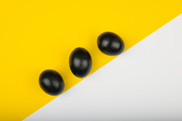 three black eggs on a yellow-white background. flat lay. Black Easter. three black eggs