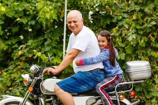 happy grandfather and his granddaughter near bike smiling