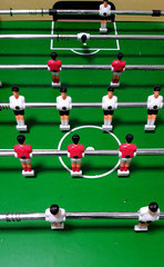 Vertical view of a vintage table soccer green playfield with players’ figurines before the game start