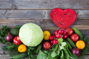vegetables are laid out in a row: cabbage, onions, cucumbers, parsley, dill, avocado, radishes, tomatoes and a heart-shaped plate with pepper