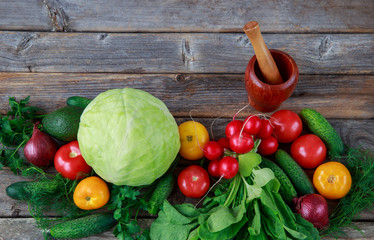 vegetables are laid out in a row: cabbage, onions, cucumbers, parsley, dill, avocados, radishes, tomatoes and a wooden mortar for pepper grinding