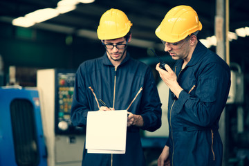 Scene of industrial workers discussing the plan and operation while writing down the note on a clipboard and another worker talking through the walkie talkie, concept manufacturer procedure.