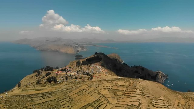 Aerial view of the Island of the Sun (Isla del Sol) in Lake Titicaca in the Andes Mountains at the border between Bolivia and Peru. Hilly dry landscape with small village surrounded by deep blue water