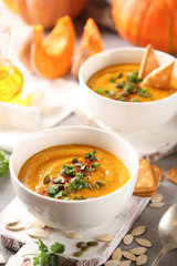 Concept of Russian cuisine. Pumpkin cream soup with cookies on a light background. Pumpkins, olive oil, spices, spoon, pumpkin seeds, herbs. Background image, copy space
