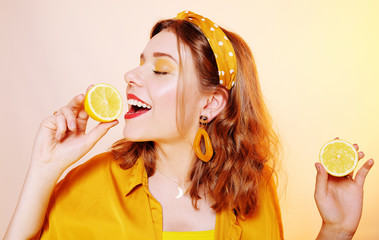 A beautiful portrait of a girl who eats a lemon, bites off a slice of lemon, a girl sniffs a lemon. Health, skin beauty, lemon-based face masks, lemon diet. Girl with bright  make-up.