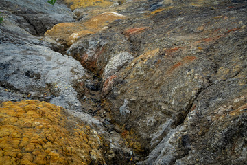 Rock fault with a crack in the mountains. The texture of the stone and lichen on it. Stone faults