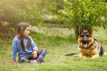 Pretty little girl, Gives a command to sit to german shepherd dog.