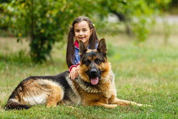 Pretty little girl, Gives a command to sit to german shepherd dog.