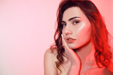 Gorgeous brunette with wrap hair portrait. Girl on a pink-red background. Beauty portrait of a girl. Professional makeup, perfect eyebrows, womans day