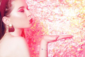 Gorgeous blonde on a bright bokeh background. Girl with pink makeup, in the style of 20x 60s. Girl on a pink background, art photo. Disco girl at the party.