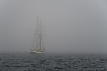 Sailing yacht in deep fog over sea