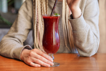 Glass of smoothie cocktail made of blackberry, blueberry, strawberry and vanilla in woman's hands
