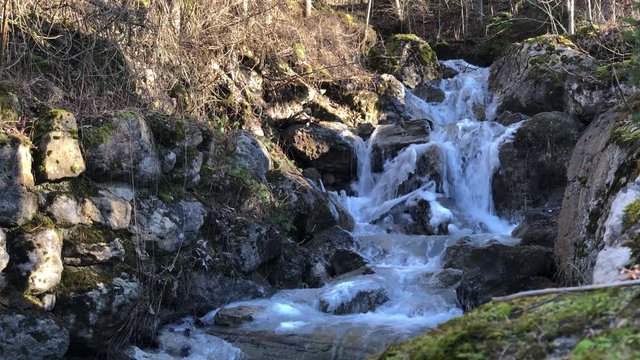 Frozen Schlattbach flowing river cascade in winter season at Switzerland, medium shot 