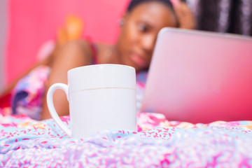 pretty african lady at home alone in her bedroom, watching a movie on her laptop pc looking scared...