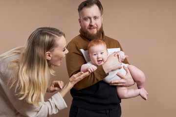 Man and a woman hold a baby in their arms. Portrait of a married couple after the birth of a child. Young family