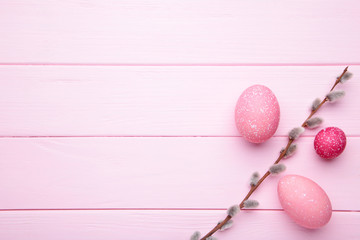 Pink easter eggs and willow branches on pink wooden background